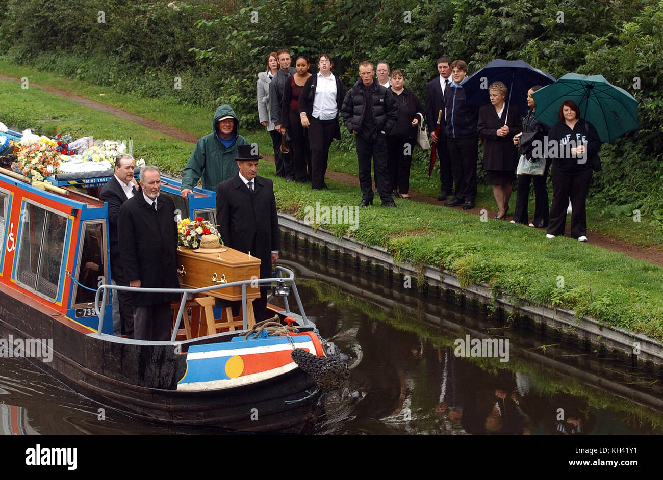 Mourners watch narrowboat carrying coffin on canal near Wolverhampton Uk Stock Photo