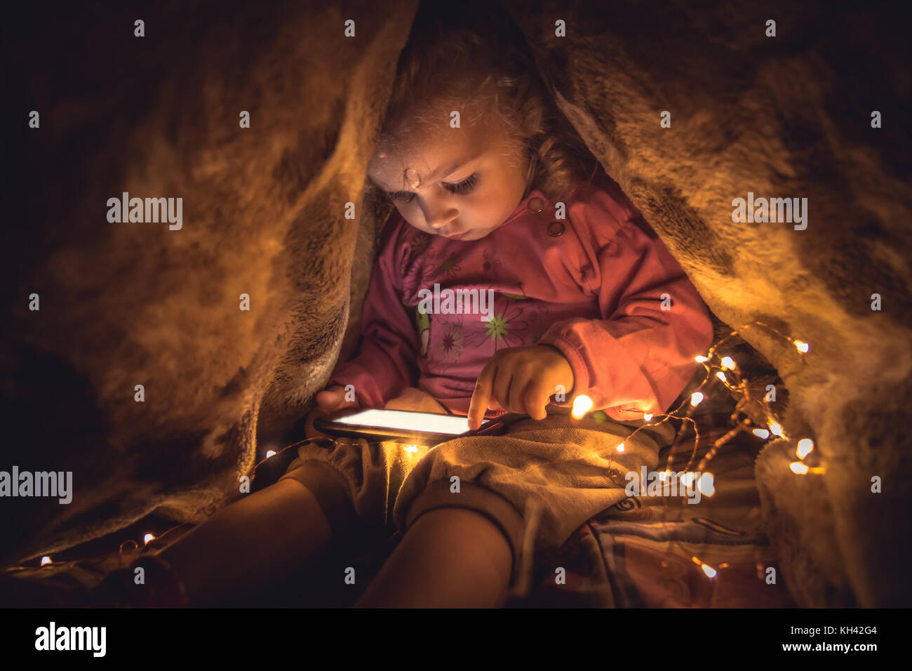 Curious child playing with smart phone hiding in secret place Stock Photo