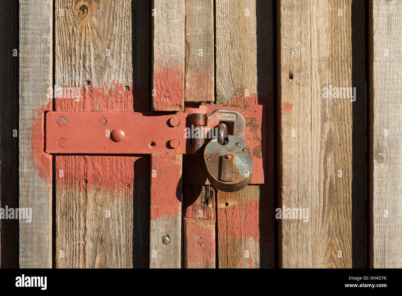 Detail of rusted metal lock on battened timber gate to a warehouse Stock Photo