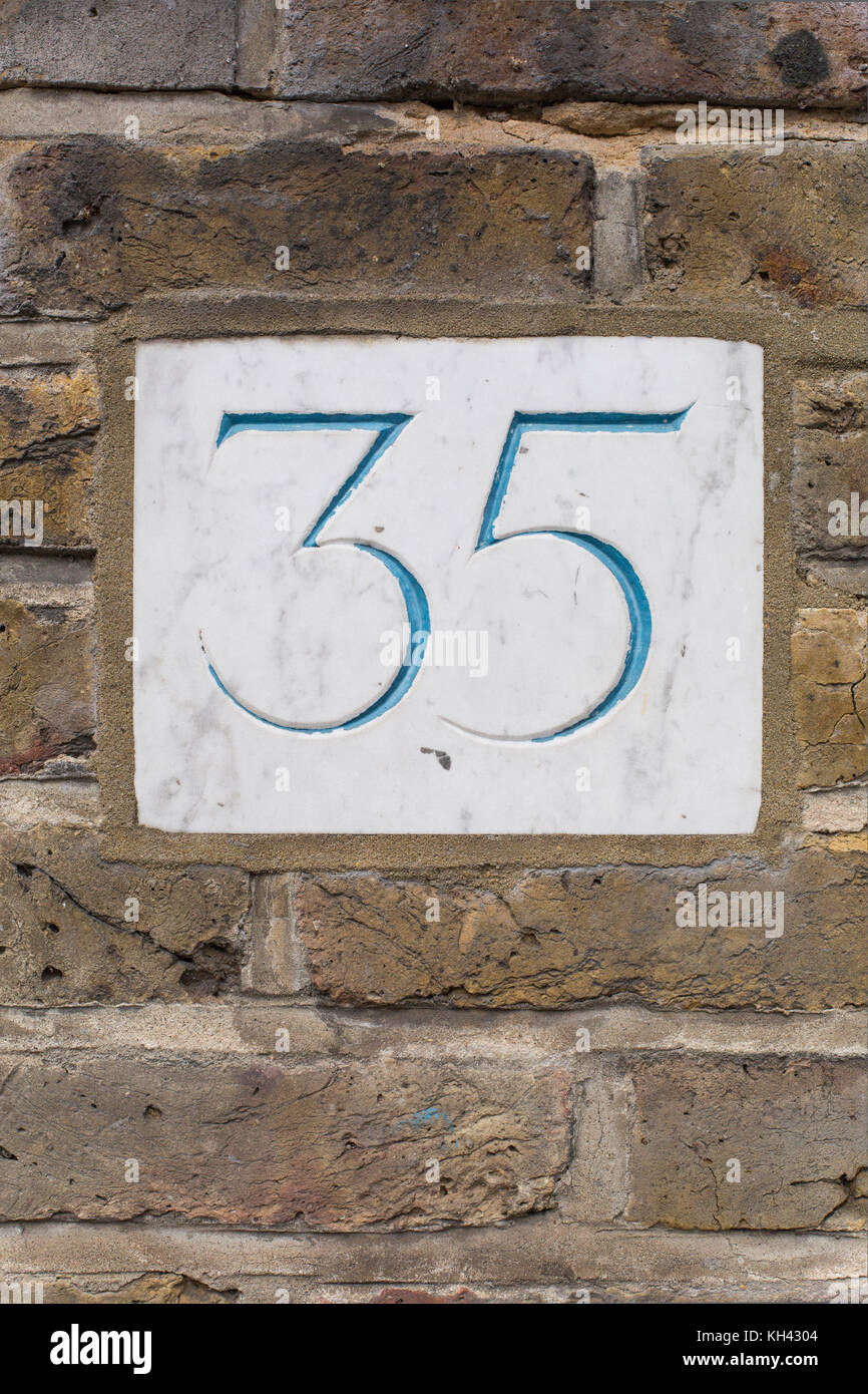 carved house number plate on brick wall Stock Photo