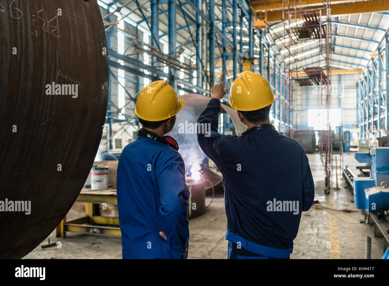 Two Asian experts talking while supervising fabrication Stock Photo