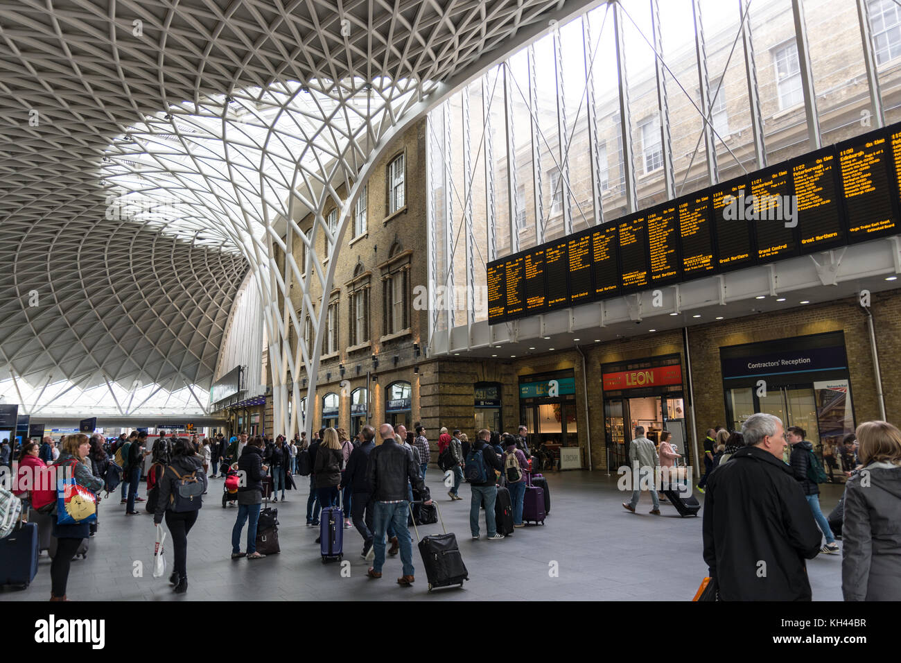 Kings Cross Station Arrivals and Departure Board with commuters and view of new roof Stock Photo