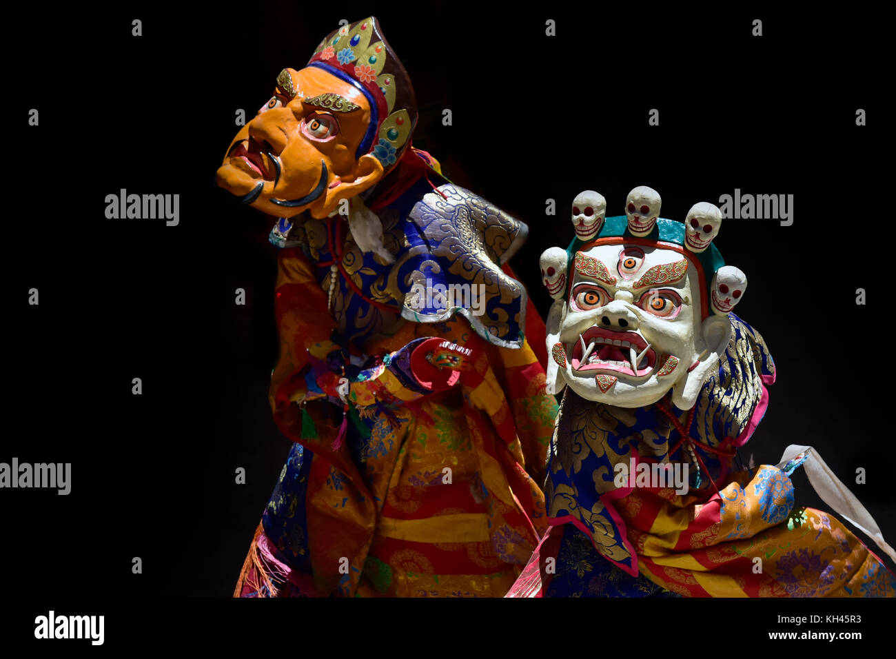 Lama dance in Masks, Cham Dance, yellow and white ancient masks and fine Tibetan clothes on a black background, Buddhist mystery, Ladakh, Himalayas. Stock Photo
