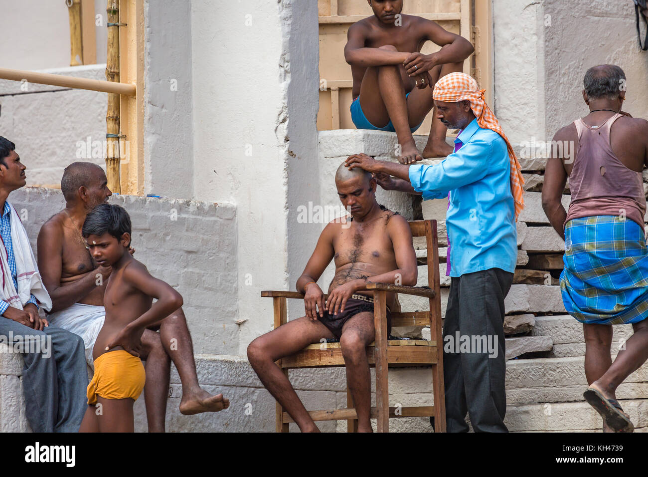 Man having his head shaved as part of a Hindu ritual at the Ganges river ghat at Varanasi India. Stock Photo