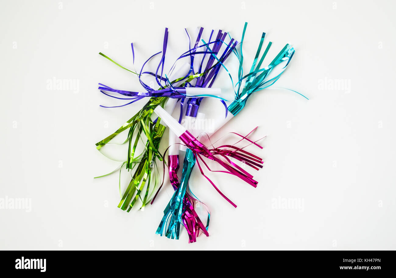 colorful party blowouts and noisemakers with streamers isolated on a solid background Stock Photo