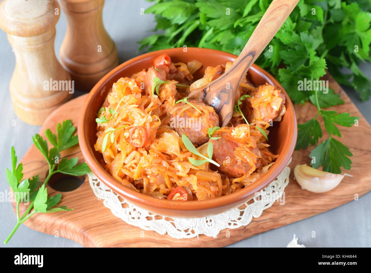 Cooked sauerkraut with sausages and spices in a traditional bowl on a wooden background. Healthy food. Home cooking Stock Photo