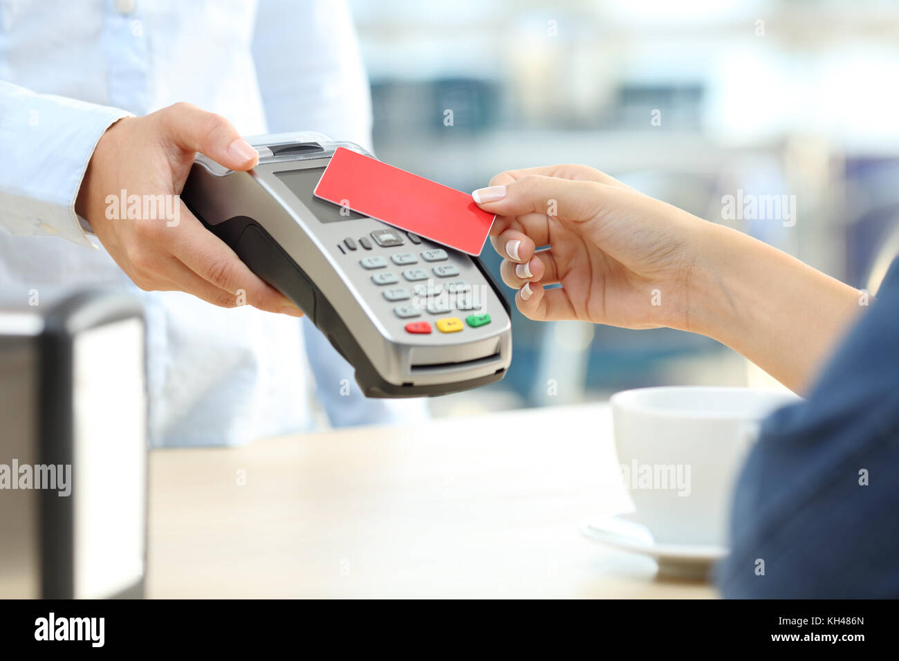 Close up of a customer hand paying with a contactless credit card reader in a bar Stock Photo