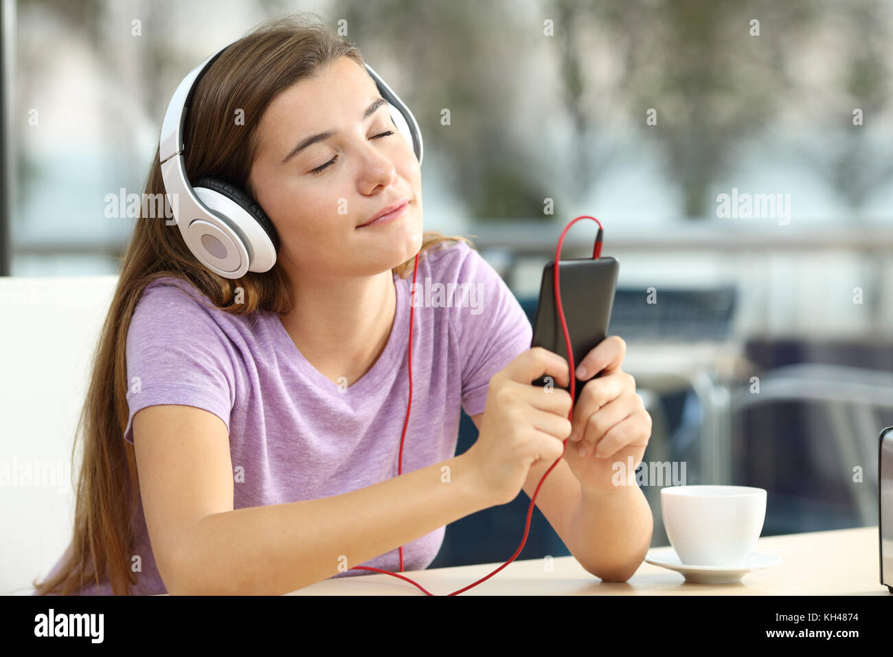 Portrait of a relaxed teen listening to music in a bar in the evening Stock Photo