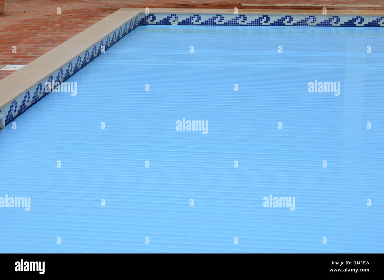 Electric slatted Swimming Pool cover on home swimming pool Stock Photo