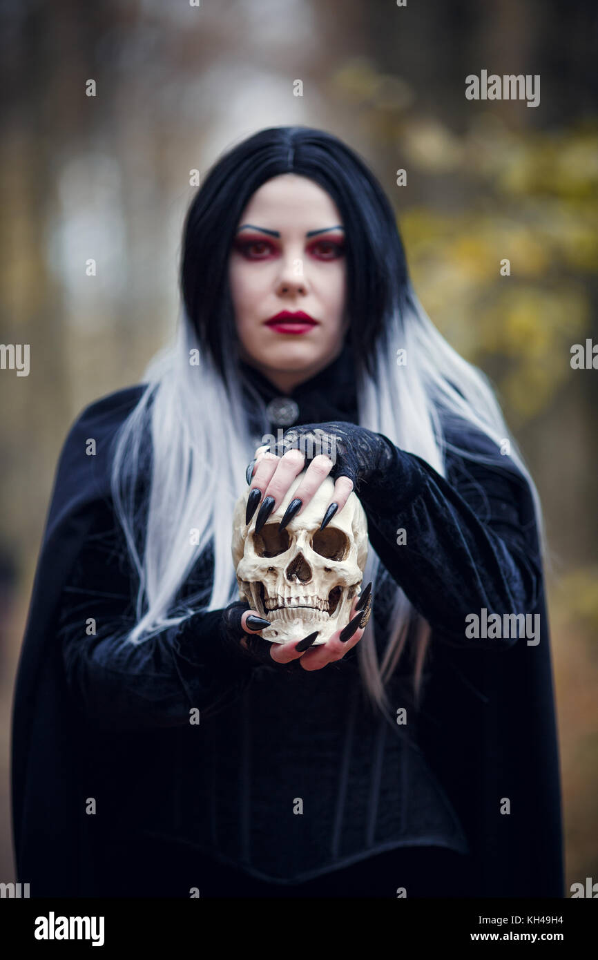 Photo Of Vampire Girl In Black Cloak With Skull In Hands Stock Photo