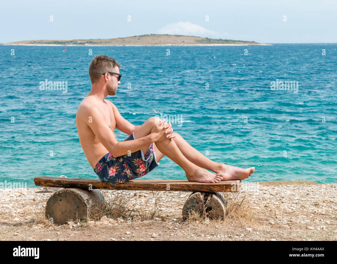 young shirthless man at the white rocky stones beach at Kamenjac National parc Porec Adriatic sea Pula Croatia Stock Photo