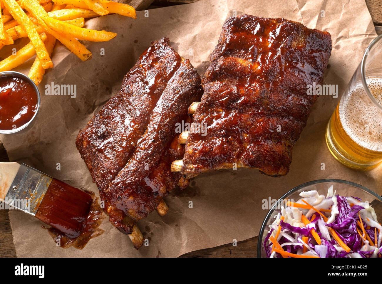 A rack of delicious baby back ribs with barbecue sauce, french fries, coleslaw and beer. Stock Photo