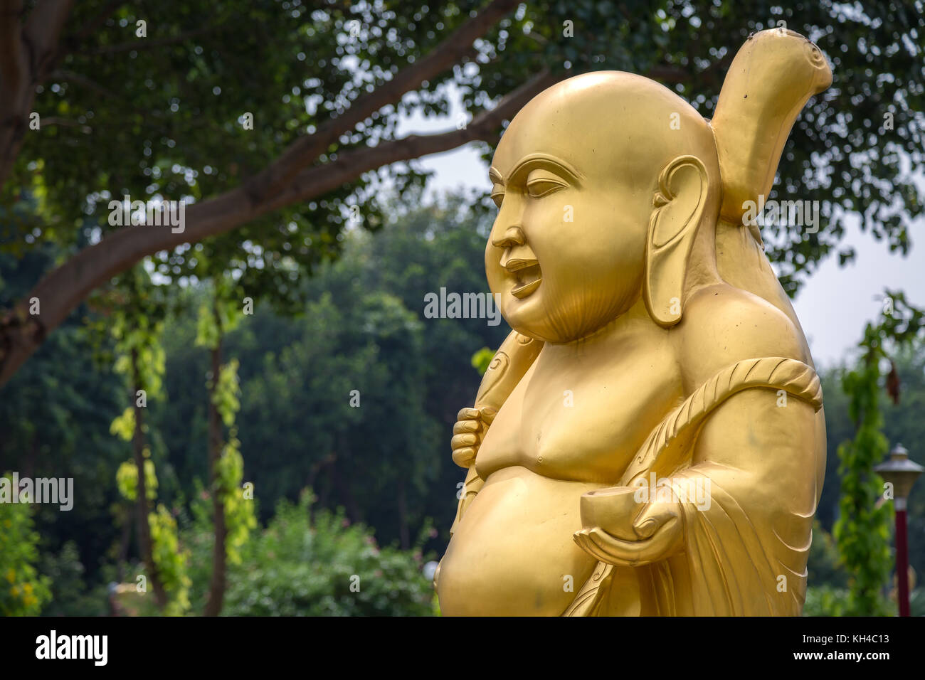 Golden laughing Buddha sculpture at Wat Thai Buddhist monastery at Sarnath, Varanasi Stock Photo