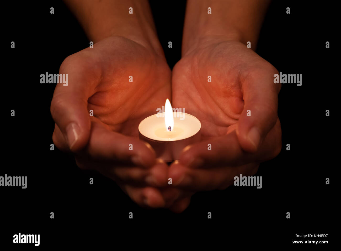 Hands holding and protecting lit or burning candle candlelight on