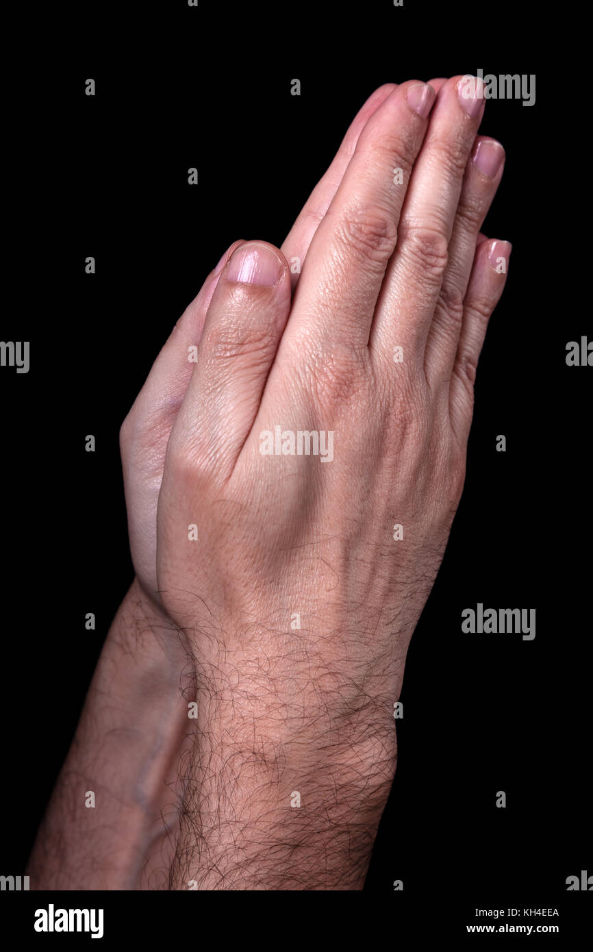 Male hands praying with palms together. Black background. Close up of man hand. Concept for prayer, pray, faith, religion, religious, worship Stock Photo