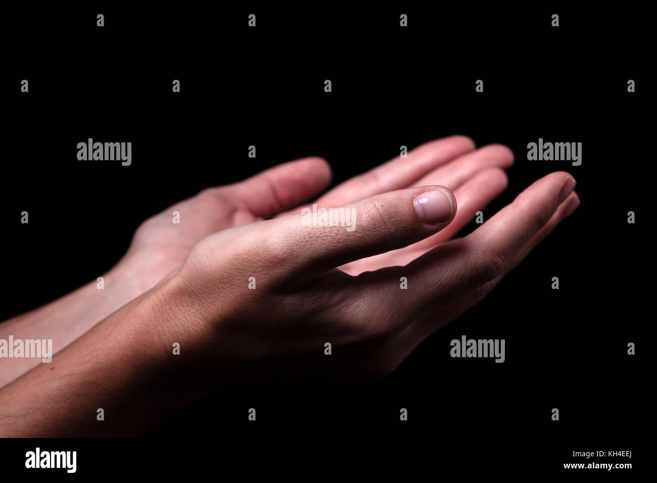 Female hands praying with palms up arms outstretched. Black background. Close up of woman hand. Concept for prayer faith religion religious worship Stock Photo