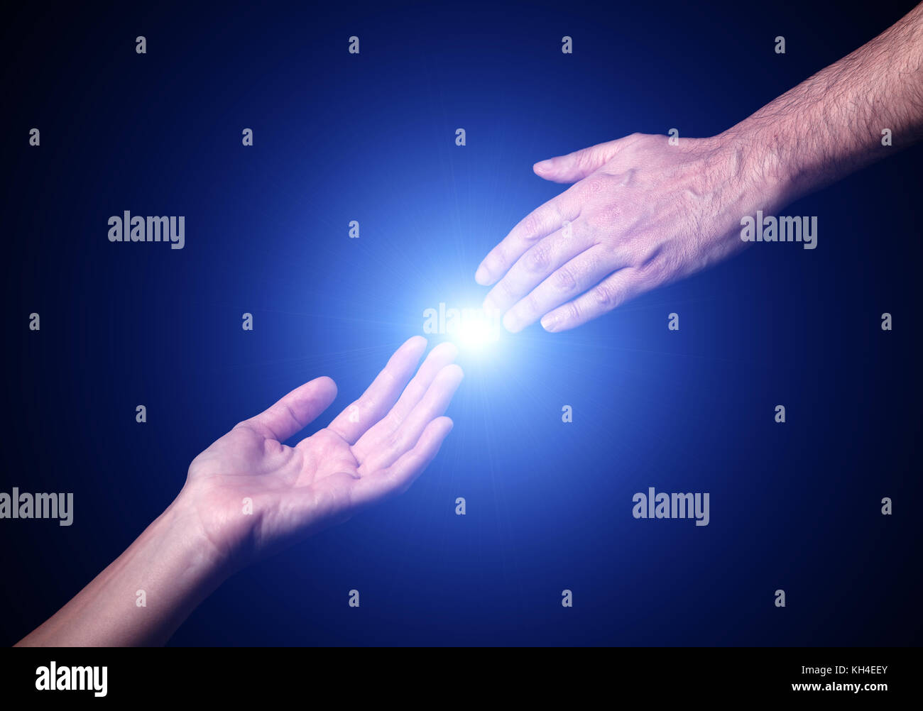 Reaching and touching hands. Bright light star flare with touching fingertips. Concept for salvation, rescue, friendship, guidance. Black background. Stock Photo