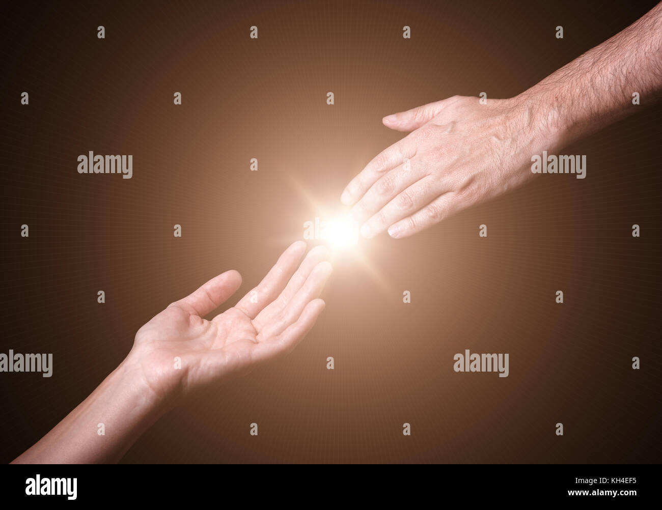 Reaching and touching hands. Bright light star flare with touching fingertips. Concept for salvation, rescue, friendship, guidance. Black background. Stock Photo