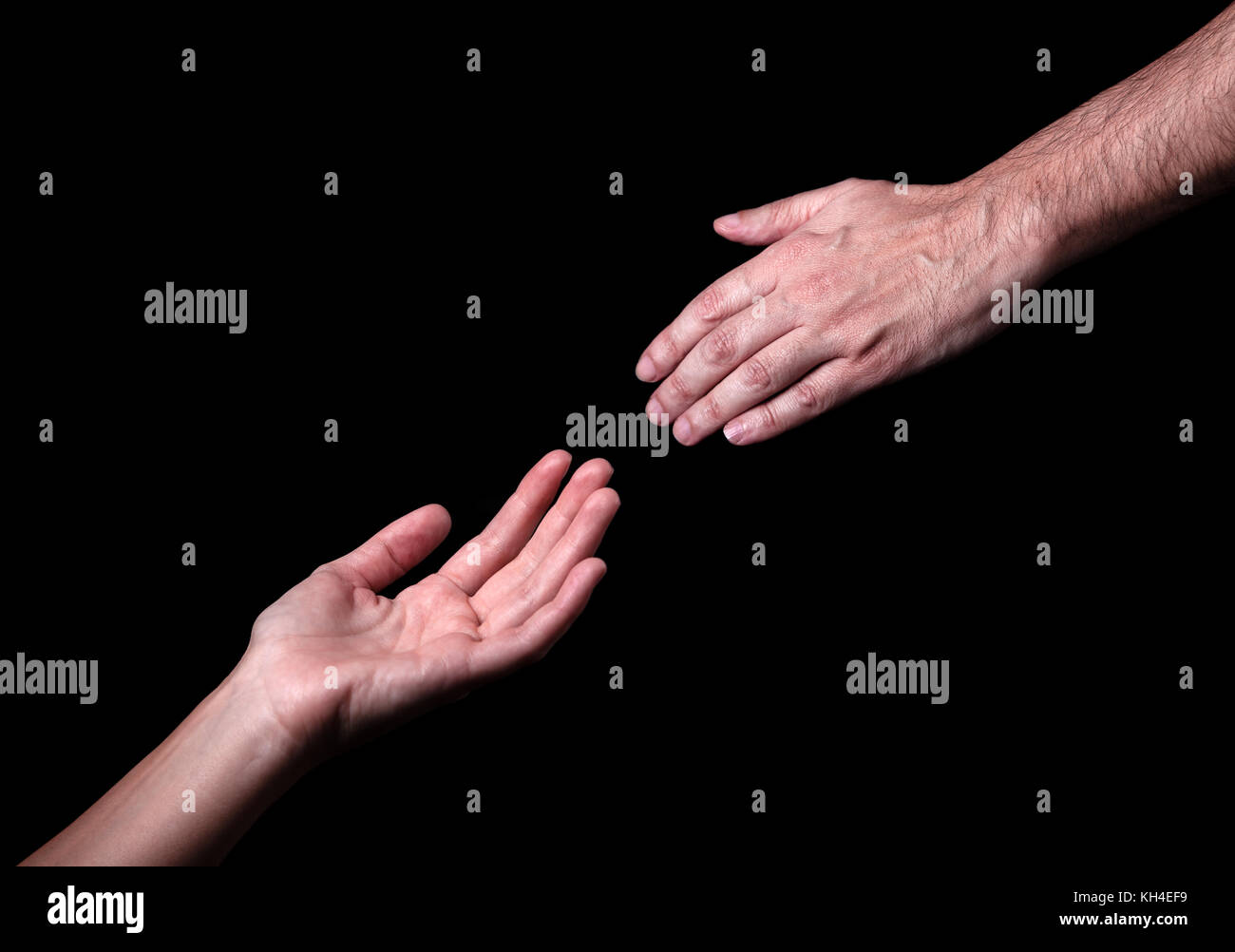 Male hand reaching to touch woman hand. Concept for salvation rescue friendship guidance help helping. Black background. God Hands Reaching Helping Stock Photo
