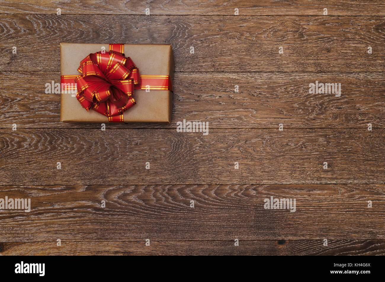 Gift with a red ribbon and bow on a dark wooden background. Christmas ...