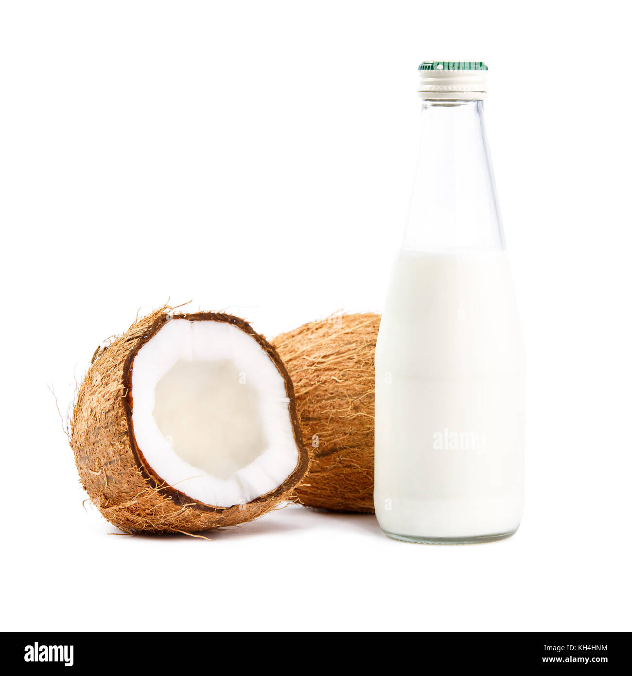 Whole and cut in half coconuts with bottle of coconut milk isolated on