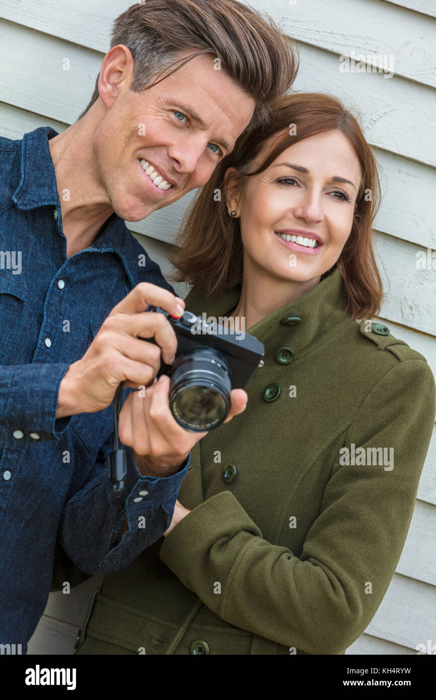 Portrait shot of an attractive, successful and happy middle aged man and woman couple together outside taking photographs with a digital camera Stock Photo