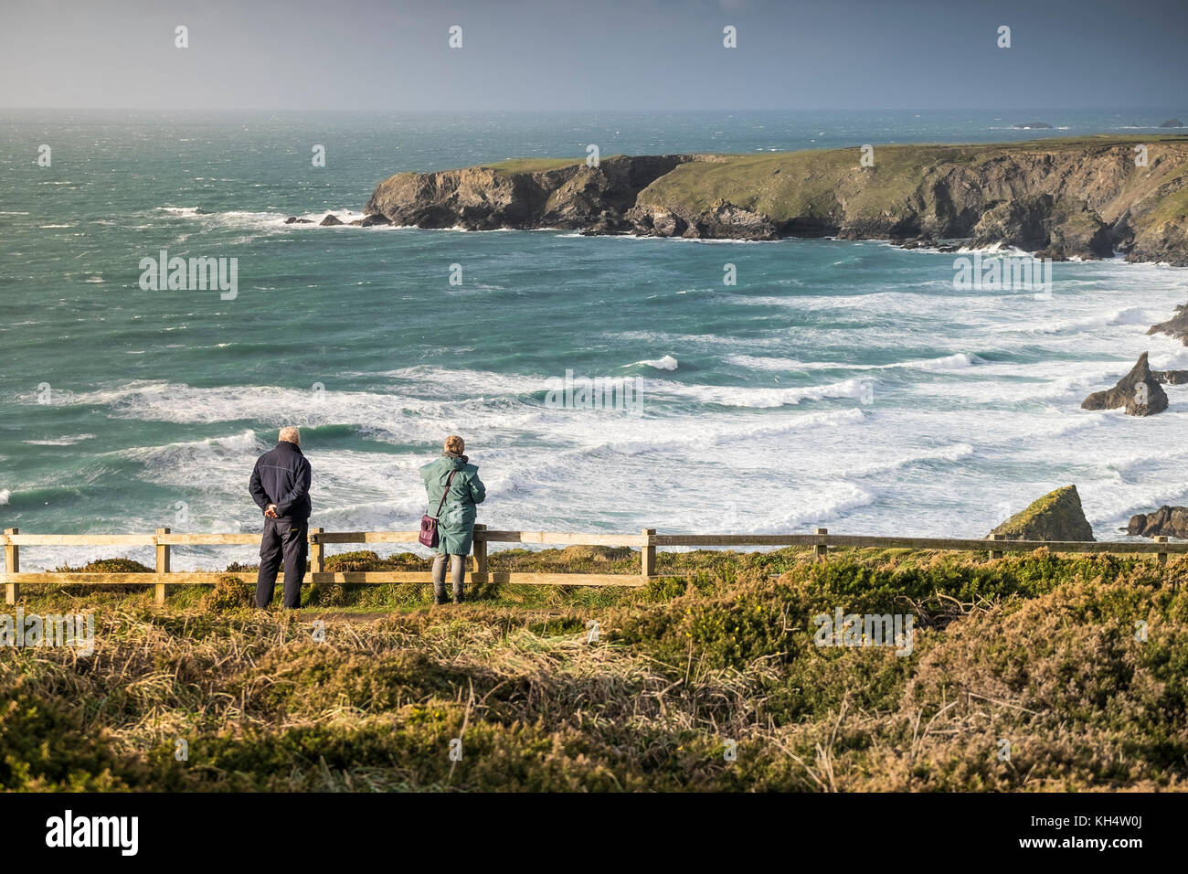 Two people standing on the South West Coast Path looking out over the sea on the North Cornwall Coast UK. Stock Photo