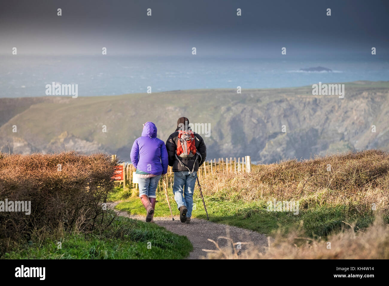 Two walkers people couple walking on a footpath at Beduthan in Cornwall UK. Stock Photo