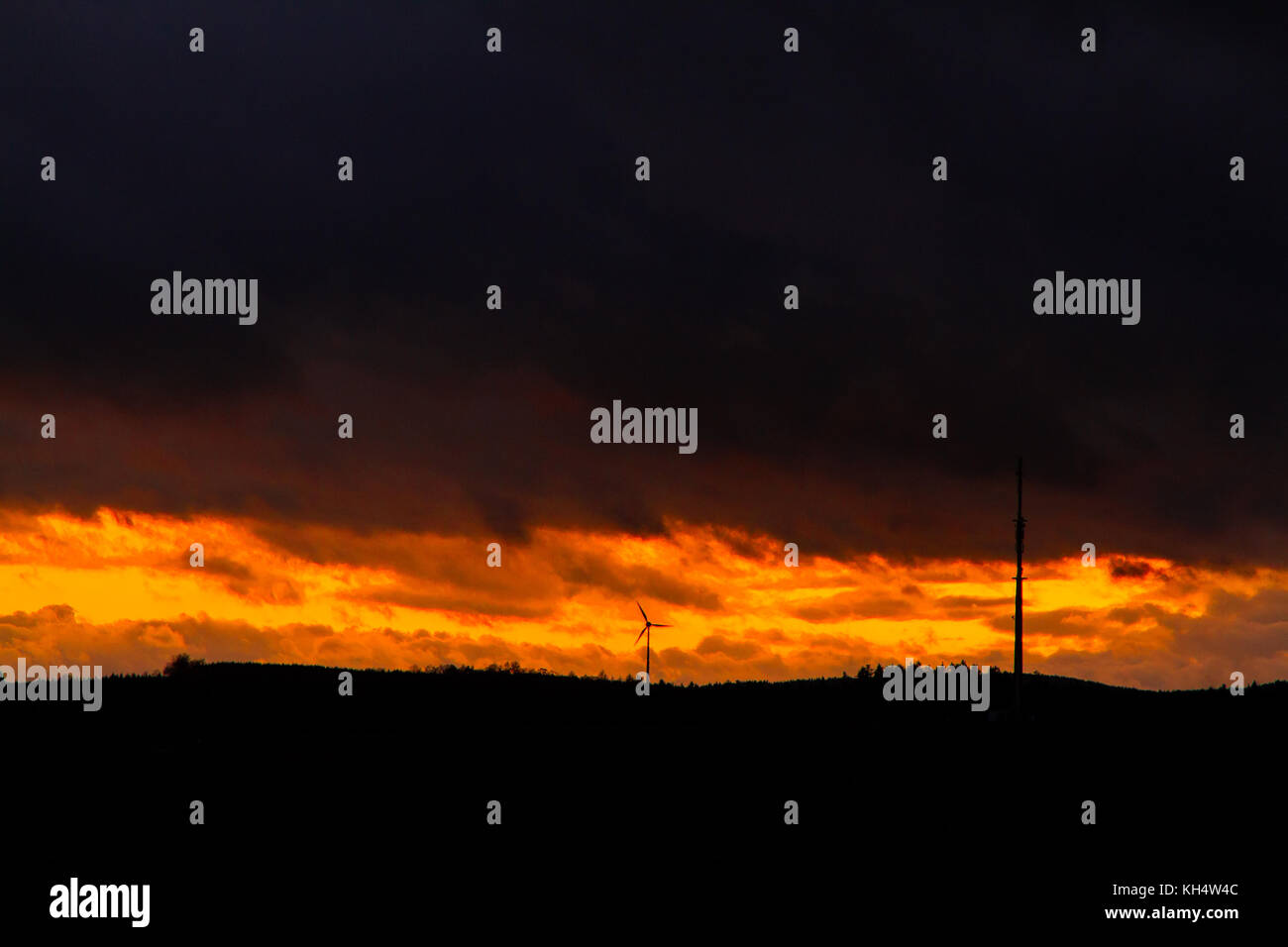 Sonnenuntergang mit dunklen Himmel Windrad und Antennenmast Stock Photo