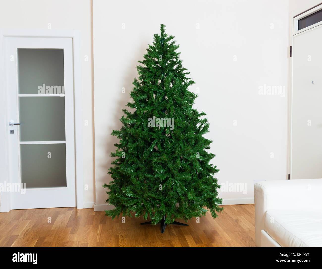 Bare artificial christmas tree in house with white furnishings and oak