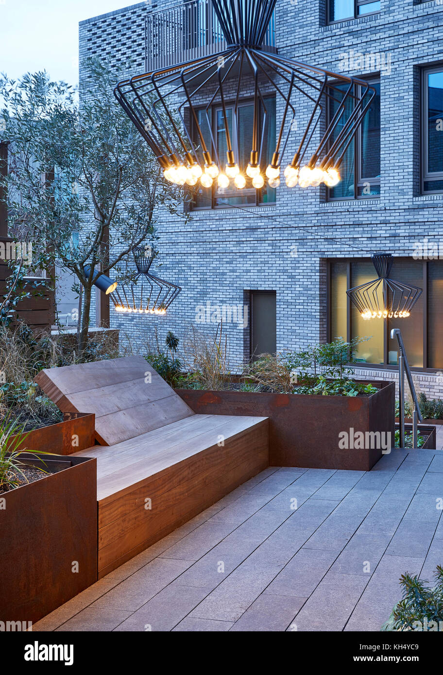 Landscaped garden with outdoor lighting features, raised metal garden beds and wooden seating. 55 Victoria Street, London, United Kingdom. Architect: Stock Photo