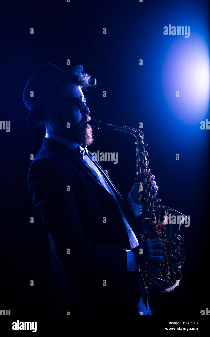 Jazz musician performing with a saxophone illuminated by a blue light Stock Photo