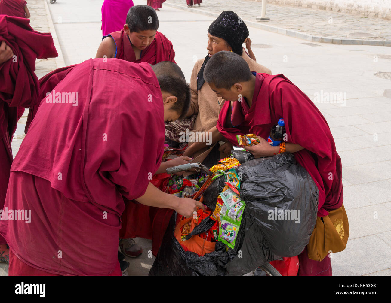 Young monks buying candies and food to a hui woman seller, Gansu province, Labrang, China Stock Photo