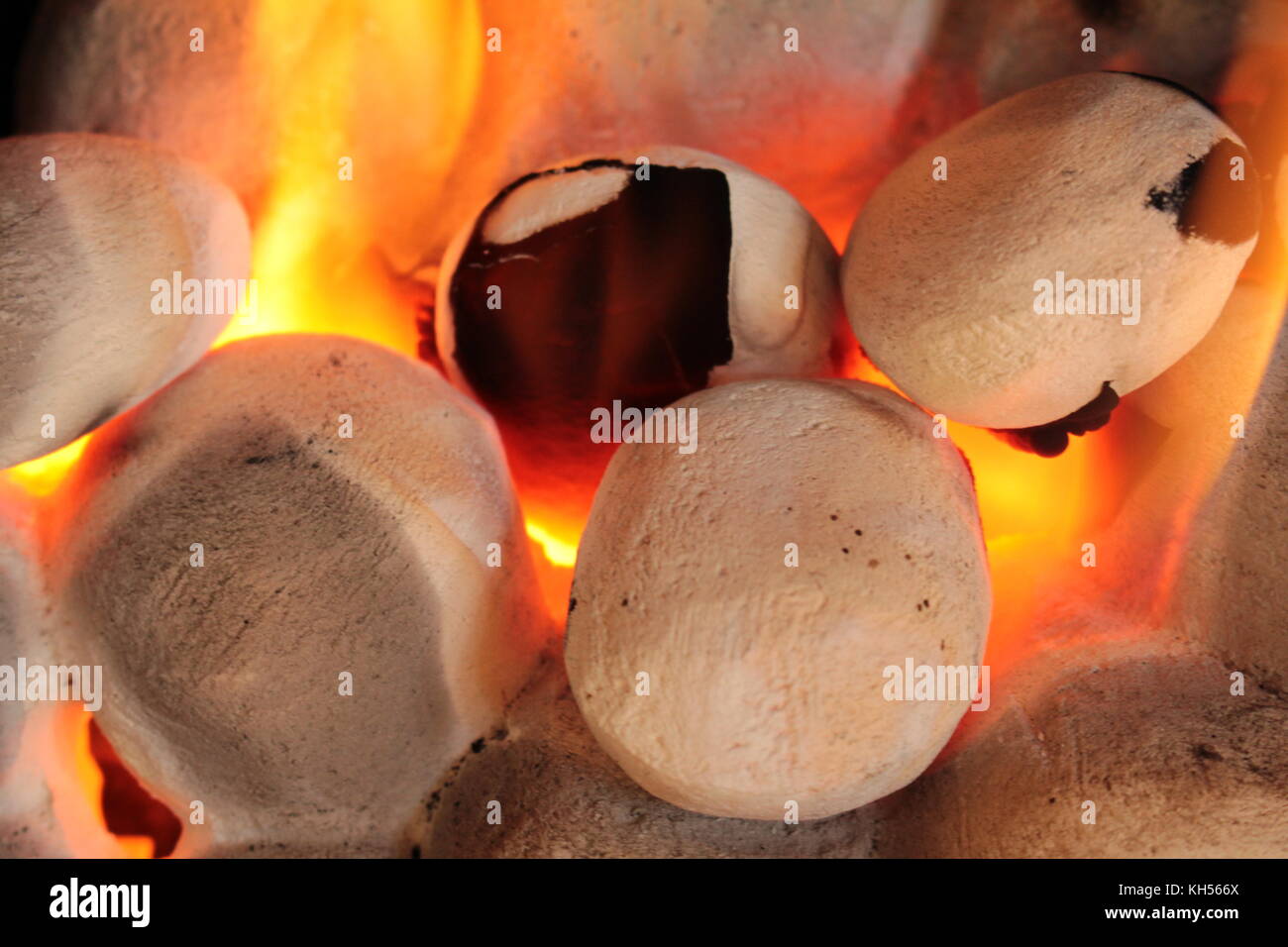 Close up of gas fire coals with yellow orange flames, glowing orange, and with soot on two of coals. Stock Photo