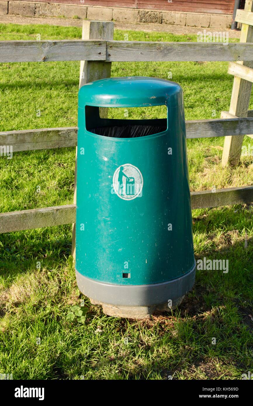 Green public litter bin from moulded plastic provided by council in England situated by a village playing field.coloured Stock Photo