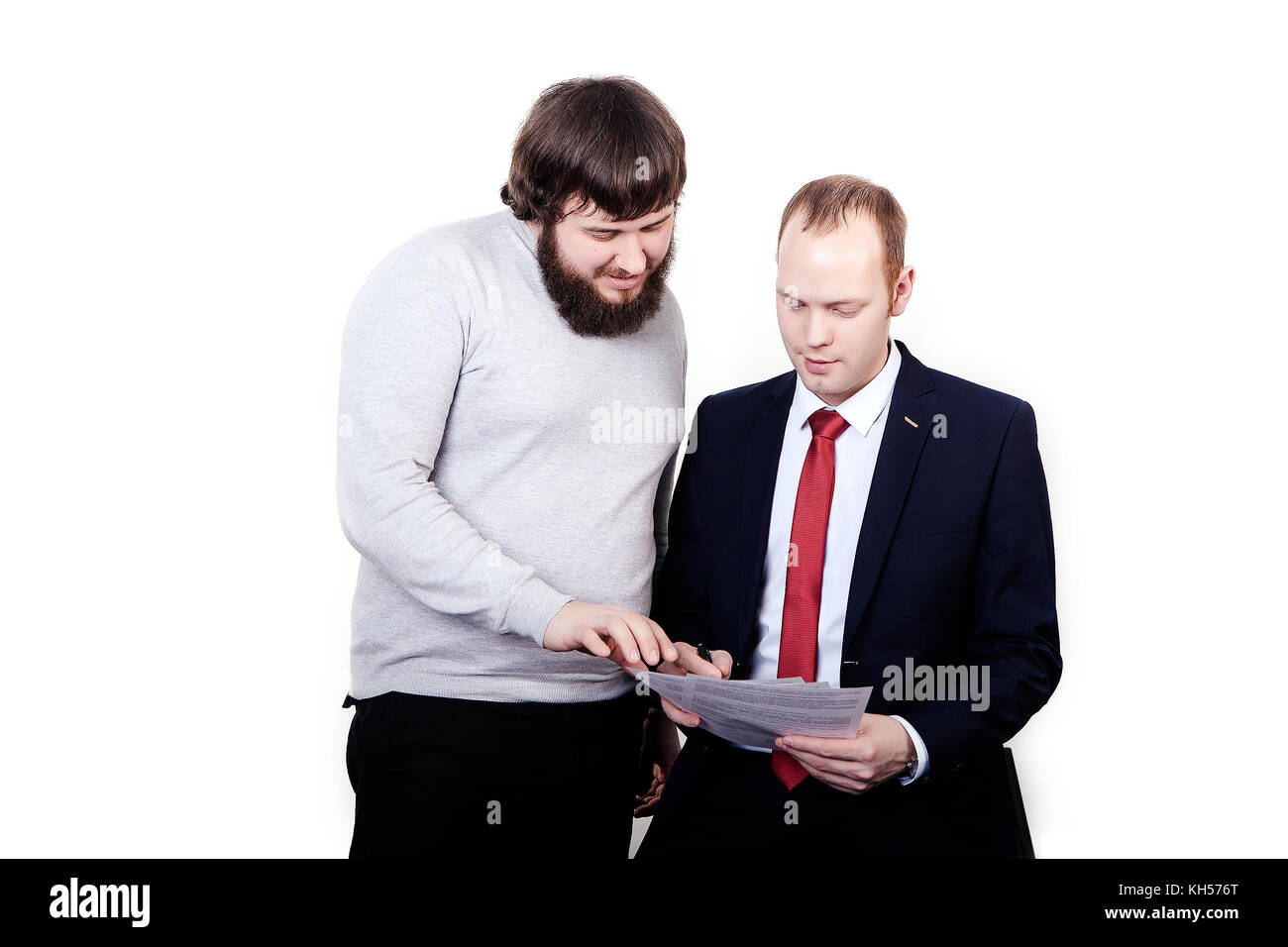 senior and junior businessman discuss and argue over something during their meeting, younger one sign contract or some documents, isolated on white Stock Photo