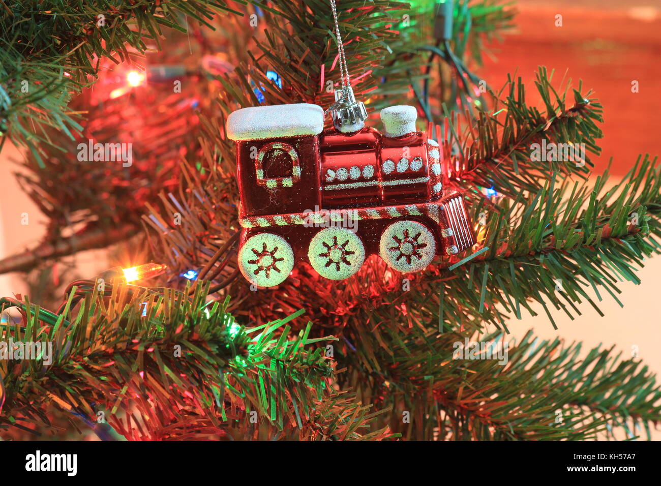 A Red Train Engine Ornament close up on a Christmas tree with Lights. Stock Photo