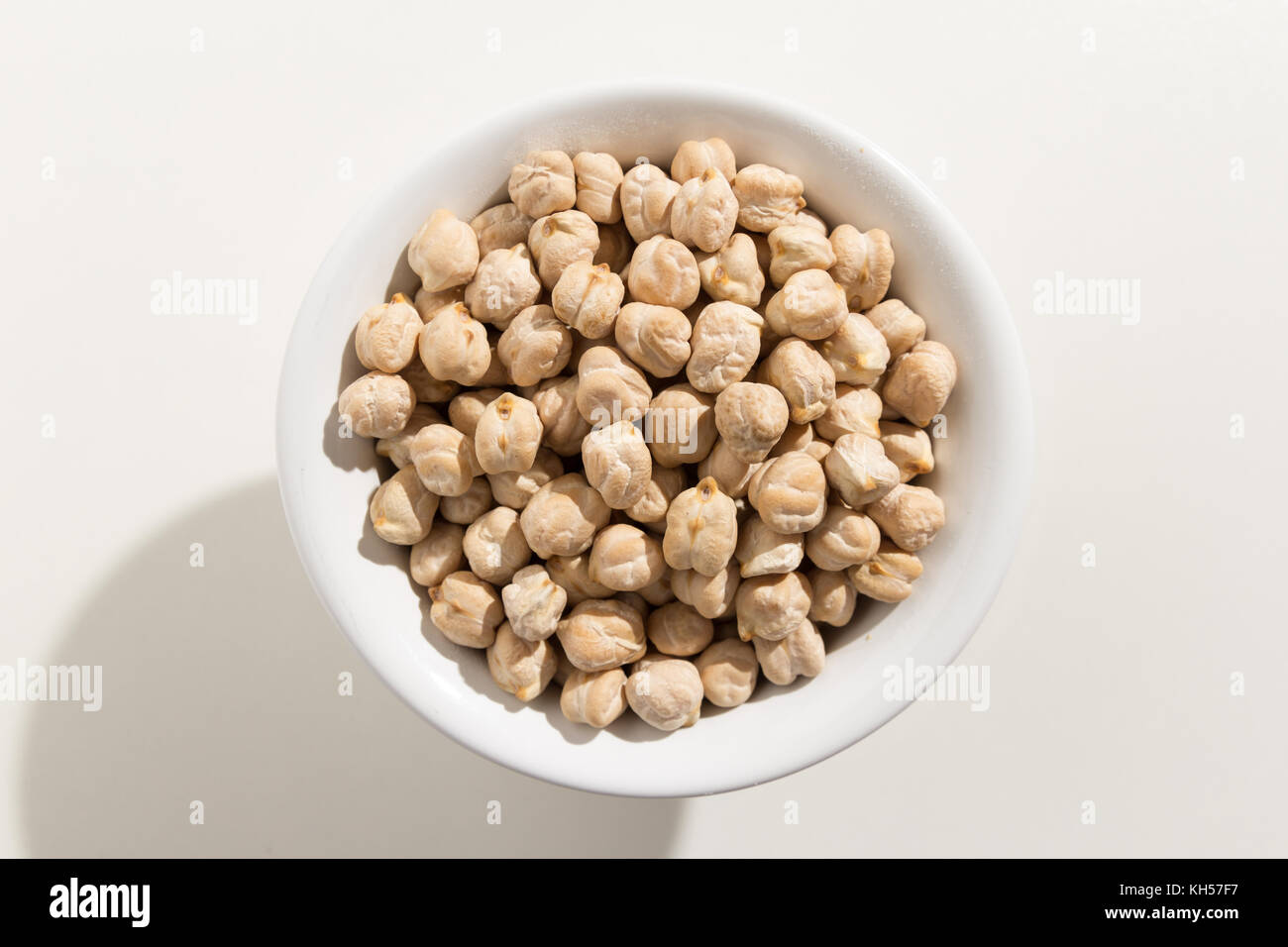 Cicer arietinum is scientific name of Chickpeas legume. Also known as Garbanzo bean, Chick Peas or Grao de Bico. Top view of grains in a bowl. White b Stock Photo