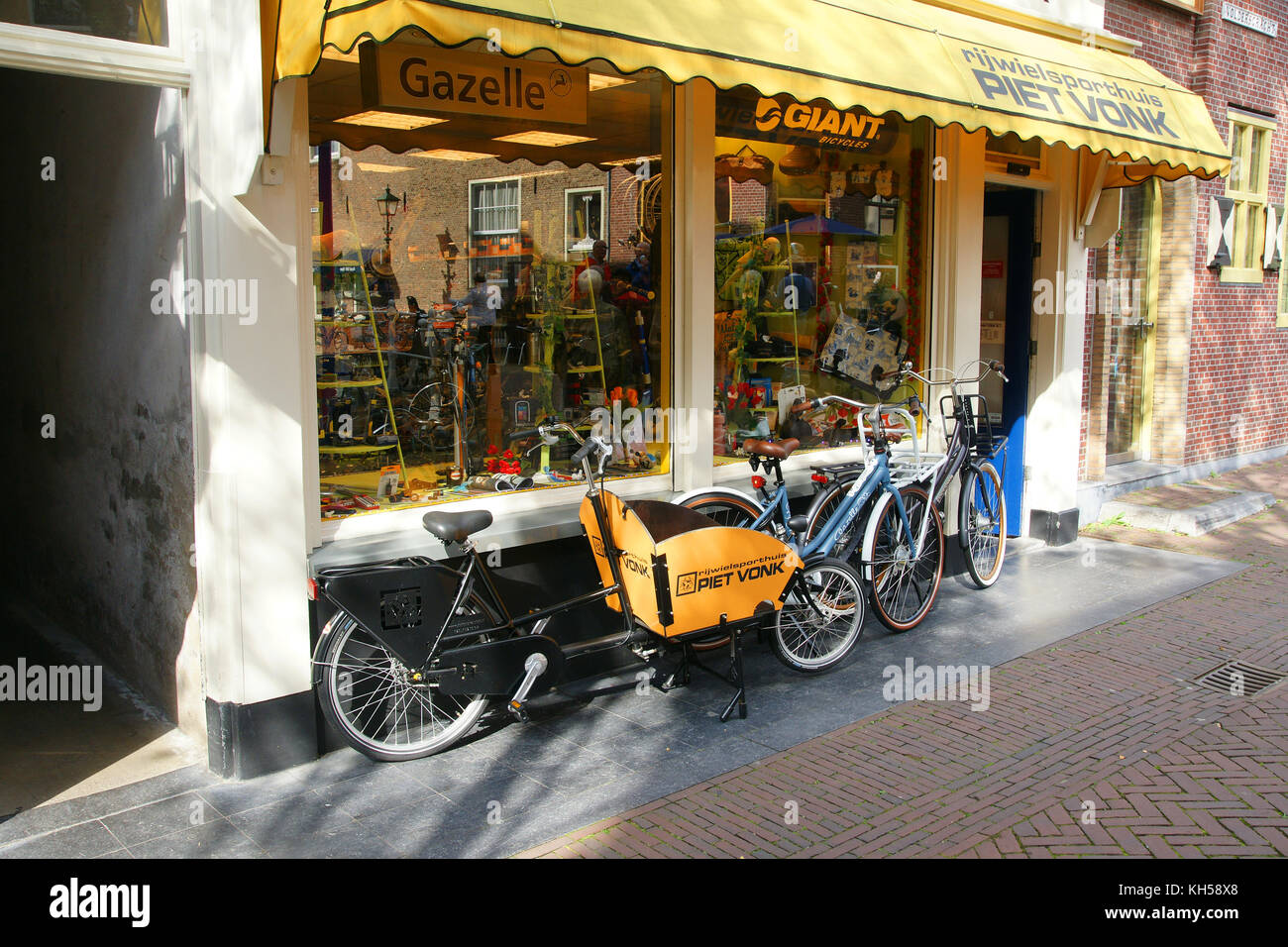 Typical Dutch bicycles including a classic cargo bike parked outside a shop in Old Delft, Netherlands Stock Photo