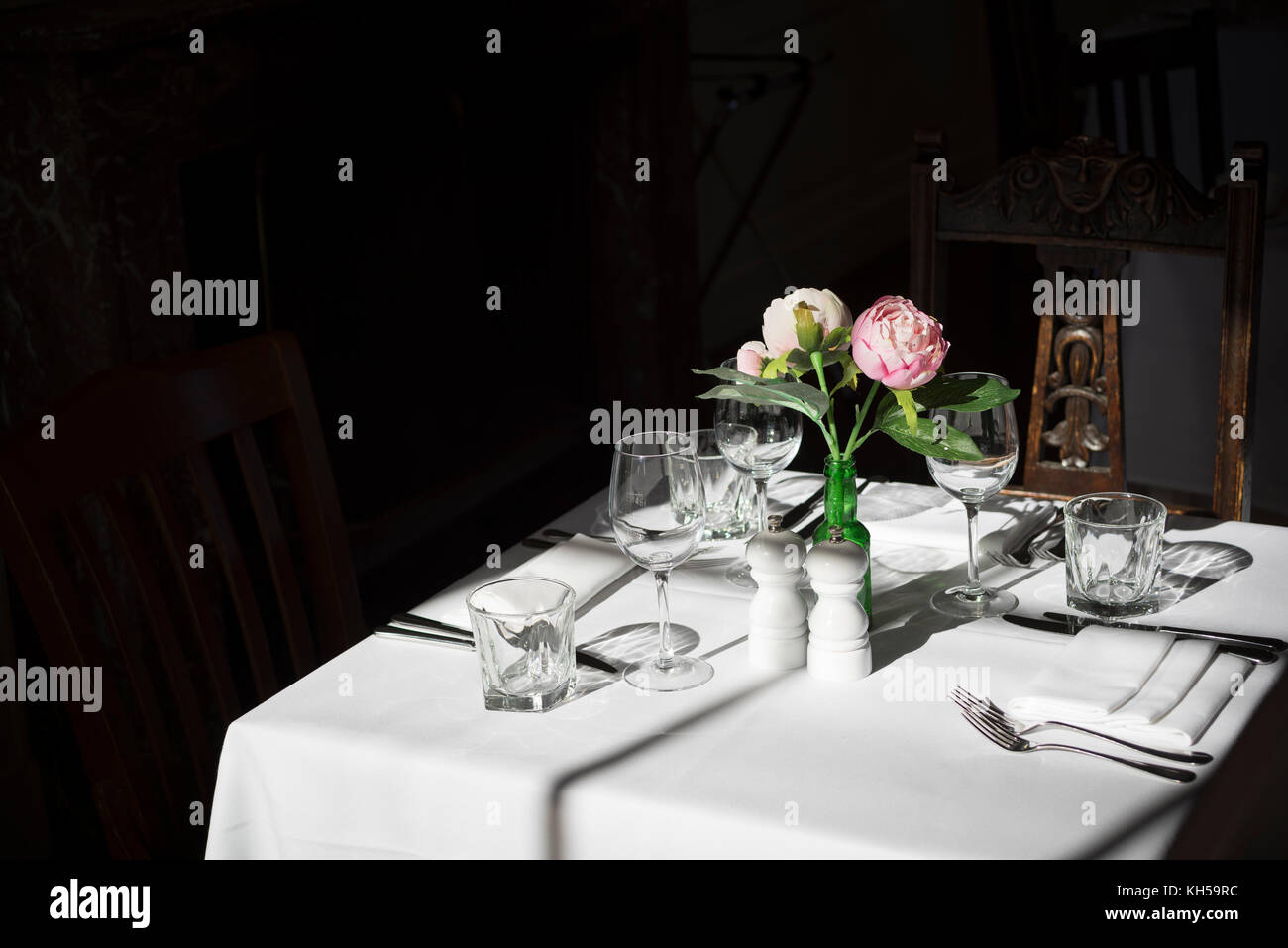 Proud Stanmer House, Brighton. Formal dining place setting with white linen and flowers, bathed in sunlight. Stock Photo