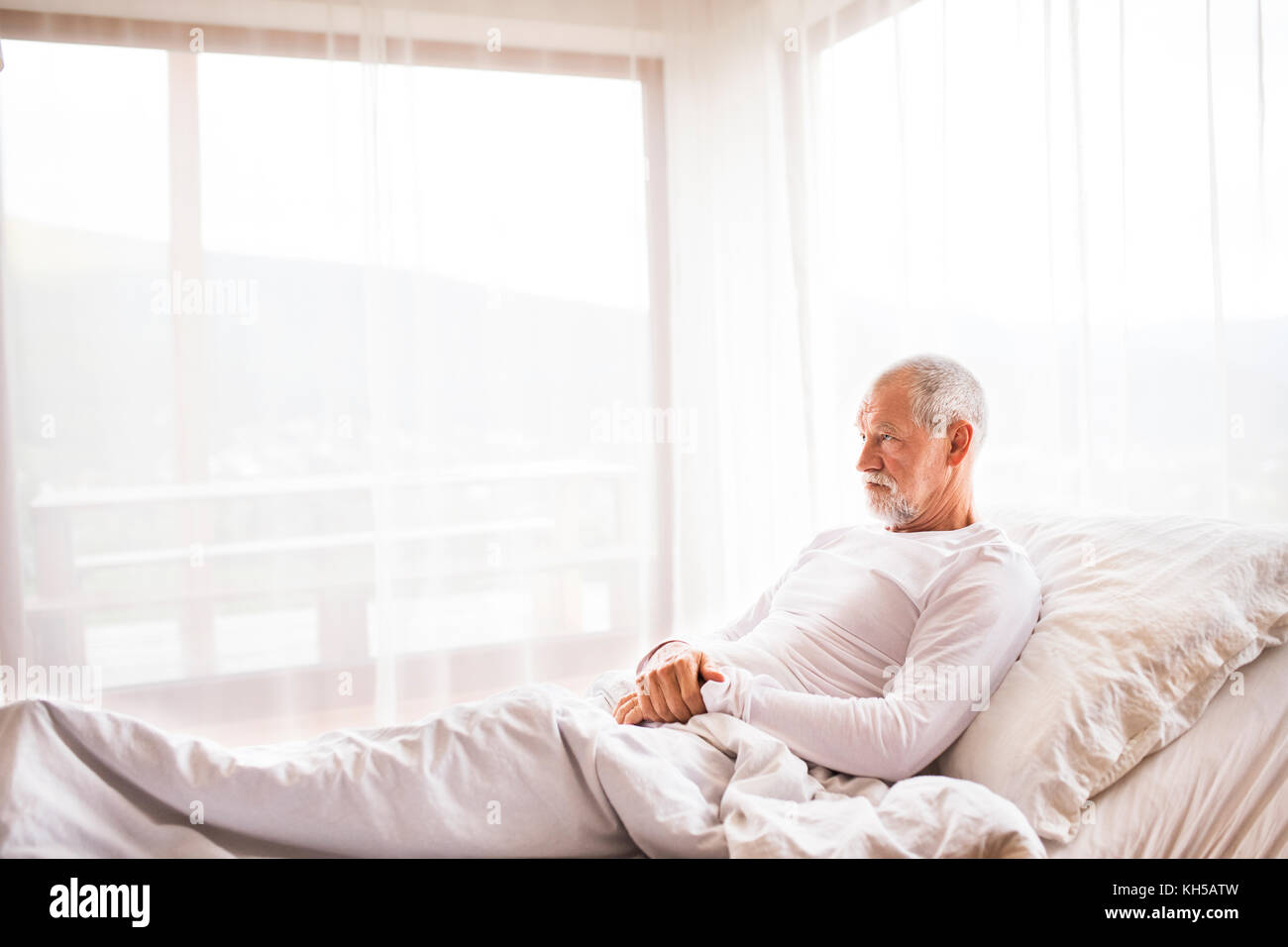 Senior man lying in bed at home Stock Photo - Alamy