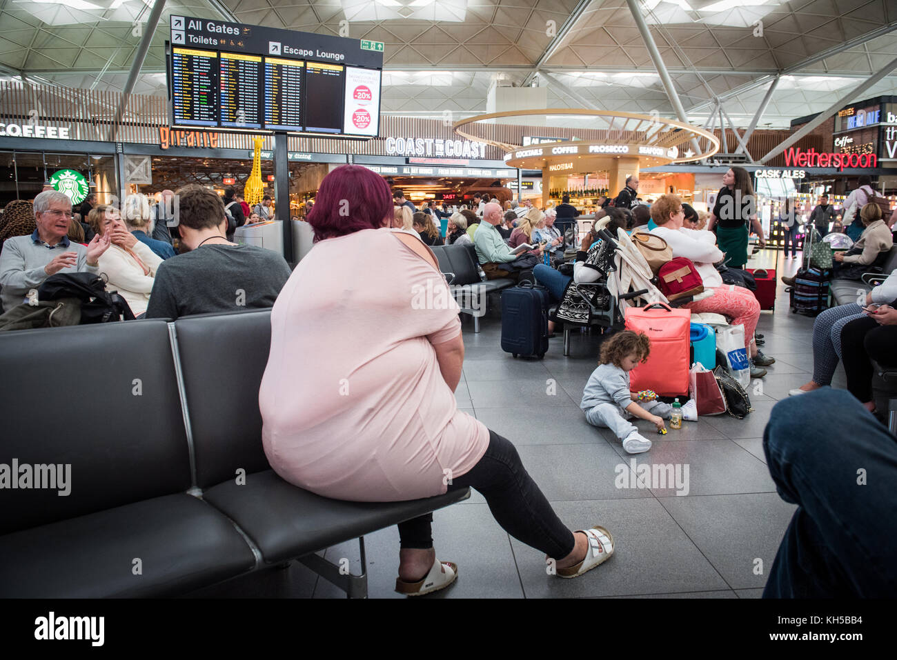 Travellers waiting for flights at Stansted Airport Stock Photo