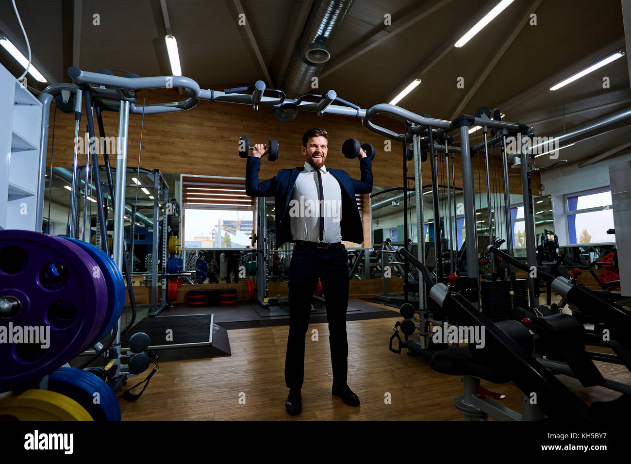 Businessman doing exercises with dumbbells in the gym Stock Photo