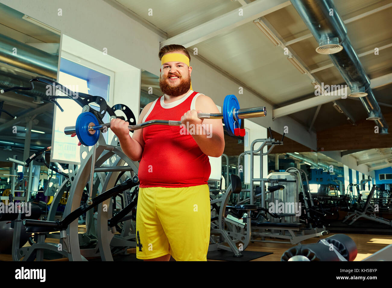 Thick man doing exercises with a barbell in the gym Stock Photo
