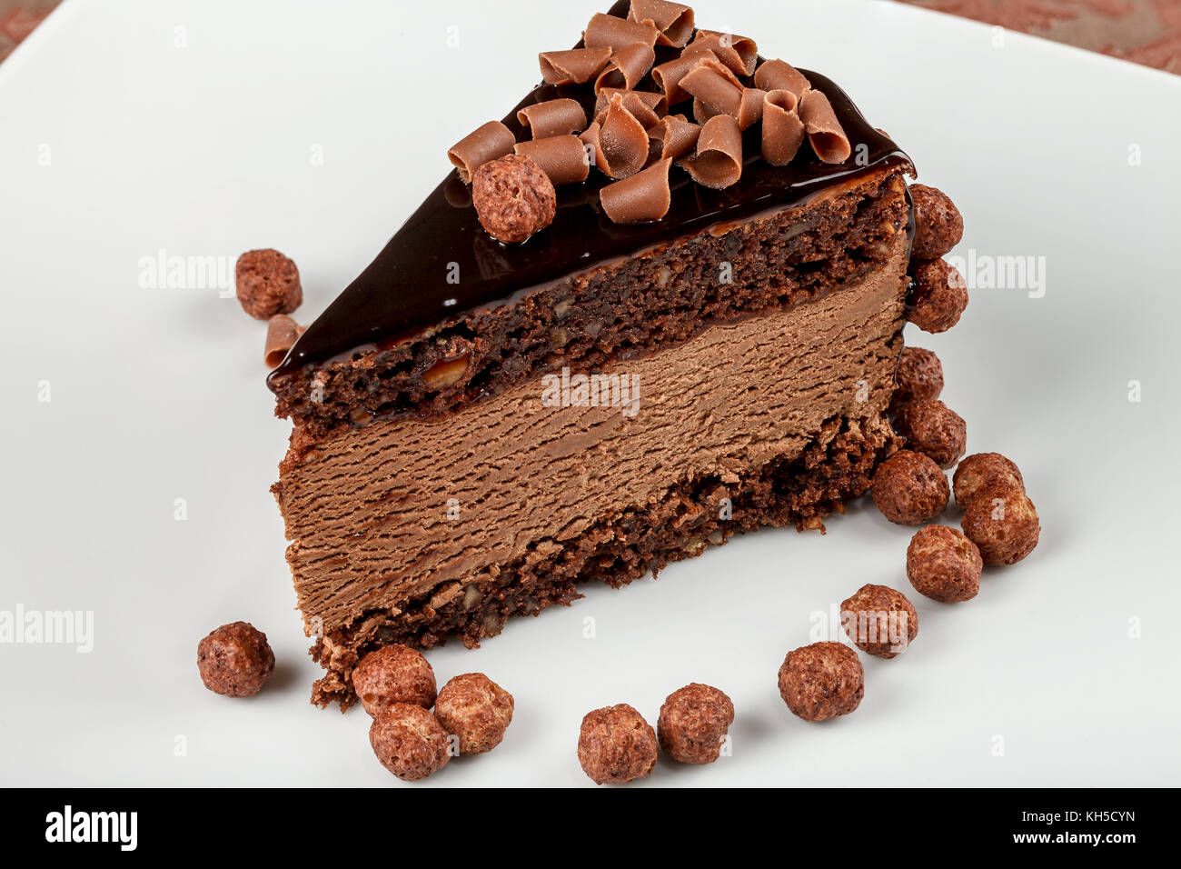 Chocolatenut cake with chocolate mousse and glaze on a white plate