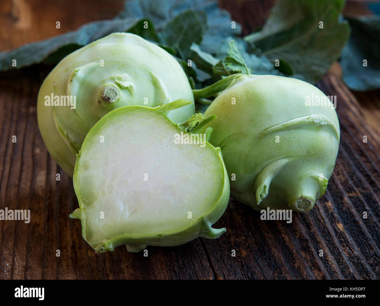 Organic fresh kohlrabi root vegetable wholes and a half on a wooden table Stock Photo