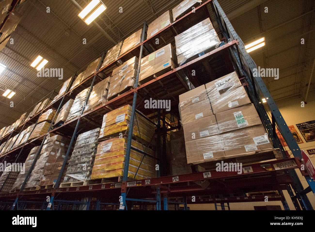 Pallets of USDA Emergency Food Assistance Program (TEFAP) commodities wait on the Houston Food Bank commodity warehouse shelves for movement to packing lines or delivery to food pantries; pallets in the aisles are loaded with disaster assistance packages (those with orange wrapping have USDA Foods in them), and are ready for delivery or distribution to those in need, in Houston, TX, on September 22, 2017. Houston Food Bank Operations Associate Director Marly Maskill provided the following information; in general, the food bank usually receives approximately 10 trucks per day and distributes ap Stock Photo