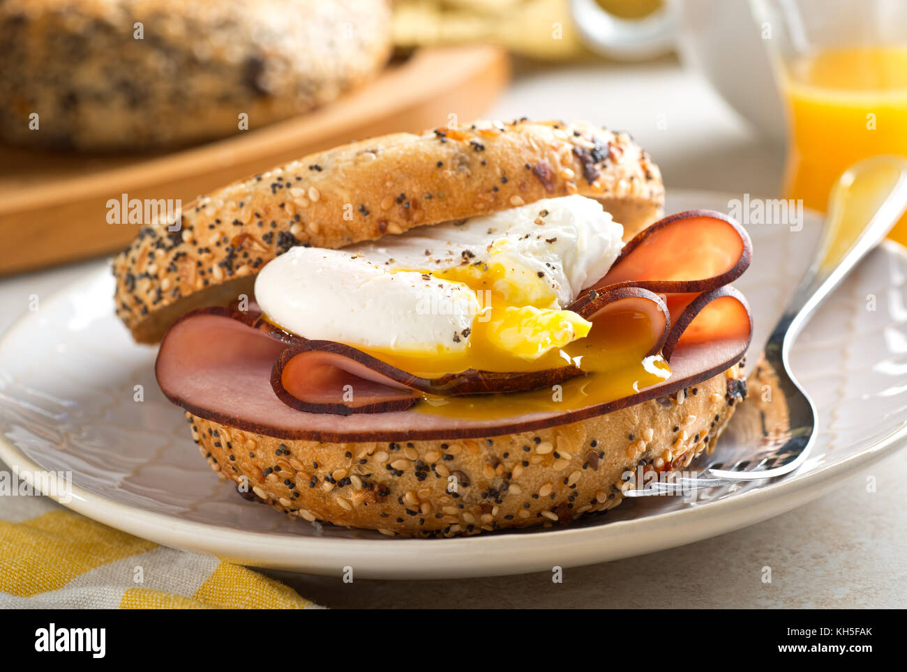 A delicious breakfast bagel with poached egg and black forest ham. Stock Photo