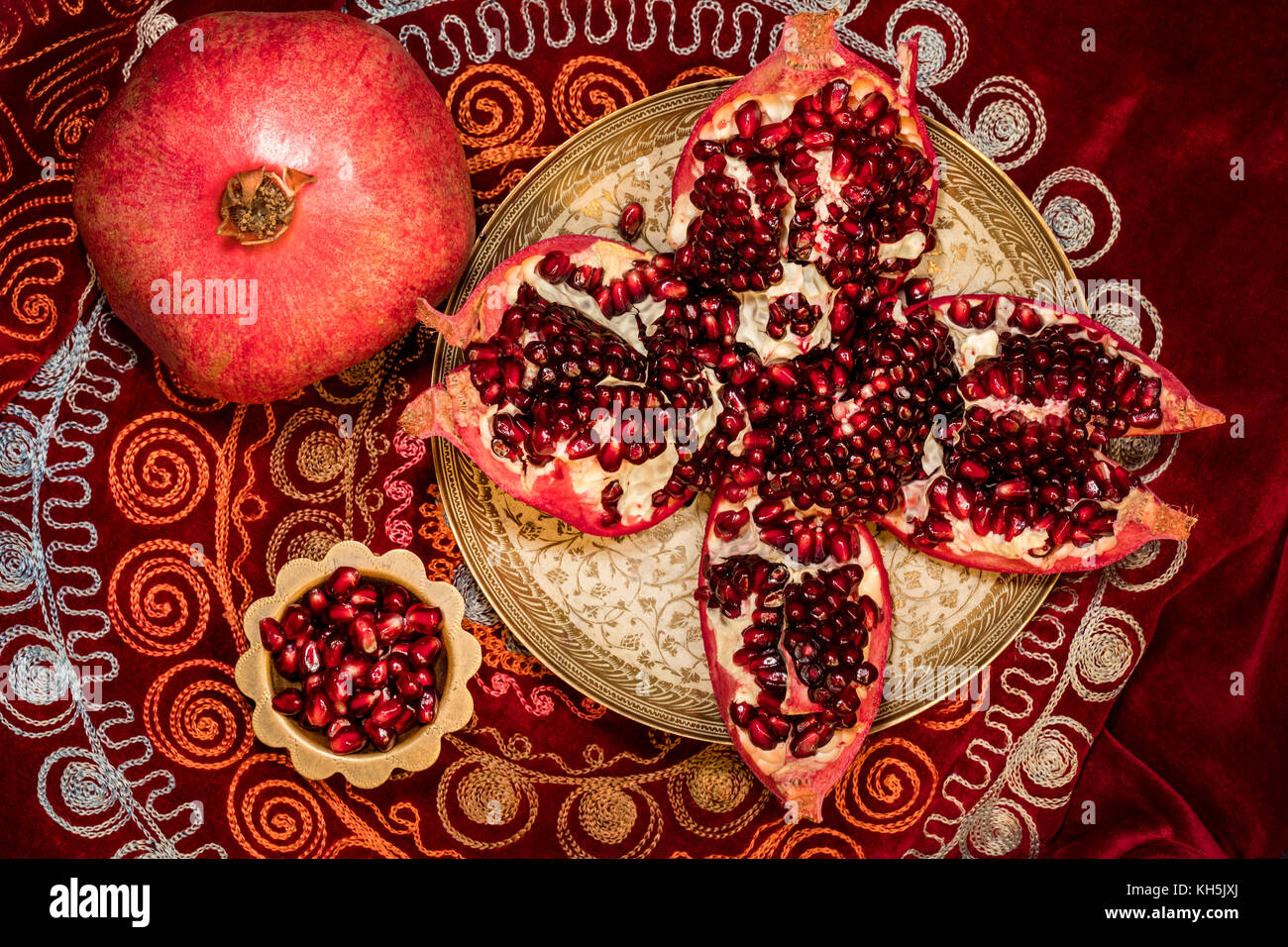 Top view of peeled pomegranate and ruby grains in a bowl on oriental tablecloth Stock Photo