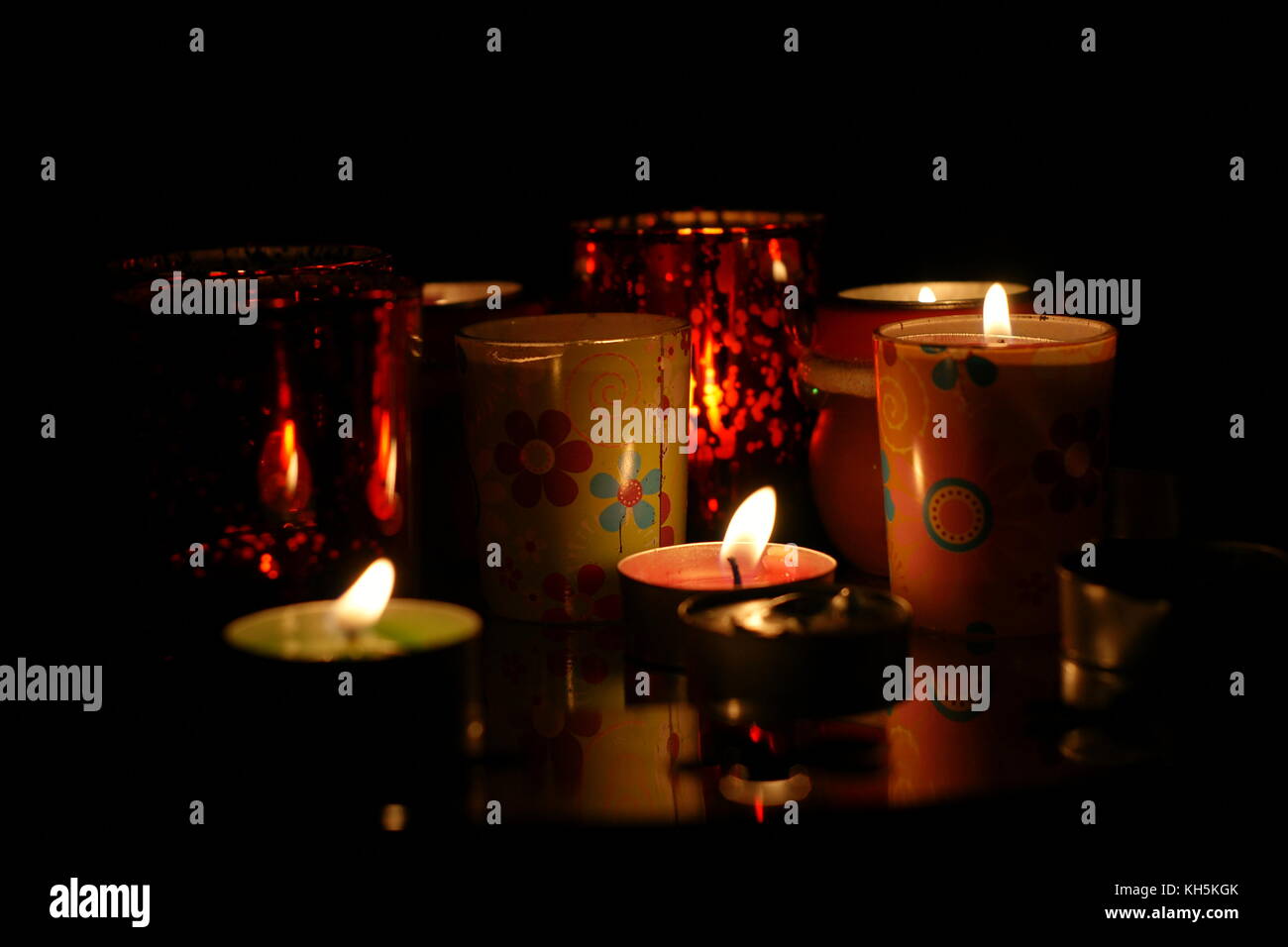 Lit candles with flames flickering in the darkness at nighttime Stock Photo